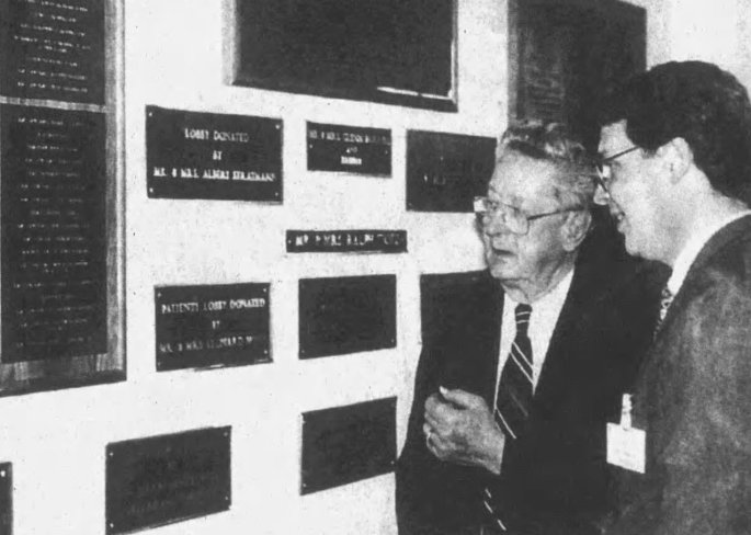 Mike McManus (right), president of St. Clement Health Services, shows the new "Wall of Honor" at St. Clement Hospital to Glenn Horrell, who chaired the fund-drive 25 years ago to build the new facility, December 1996 (Waterloo Republic-Times)